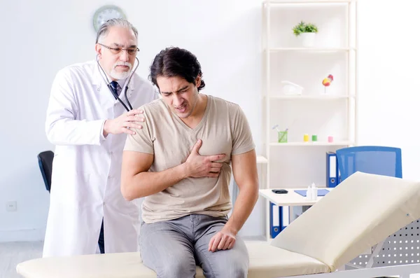 Jovem paciente do sexo masculino visitando médico velho — Fotografia de Stock