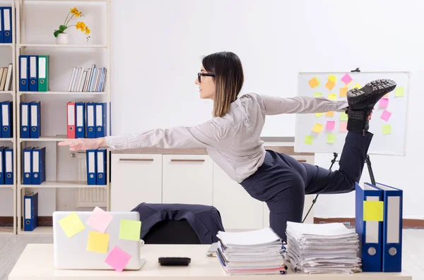 Mladá zaměstnankyně dělá cvičení na pracovišti — Stock fotografie