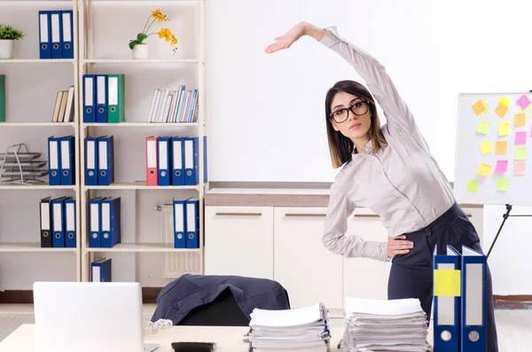 Giovane impiegata che fa esercizi sul posto di lavoro — Foto Stock