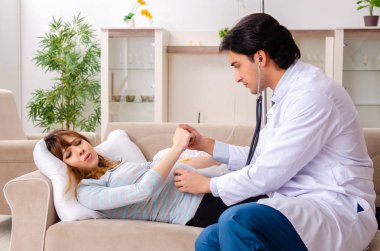 Genç, yakışıklı doktor hamile kadını ziyaret ediyor. 