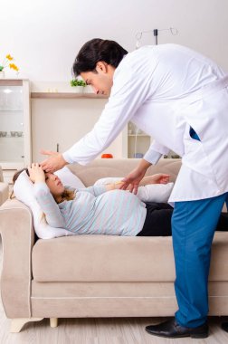 Genç, yakışıklı doktor hamile kadını ziyaret ediyor. 