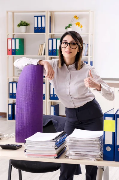 Jovem funcionária fazendo exercícios no local de trabalho — Fotografia de Stock