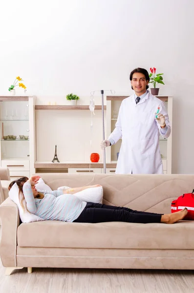 Jovem médico bonito visitando mulher grávida em casa — Fotografia de Stock
