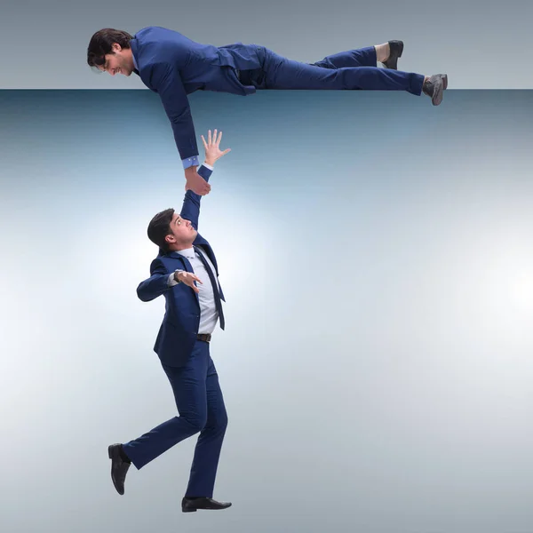 Businessman offering helping hand to falling colleague — Stock Photo, Image