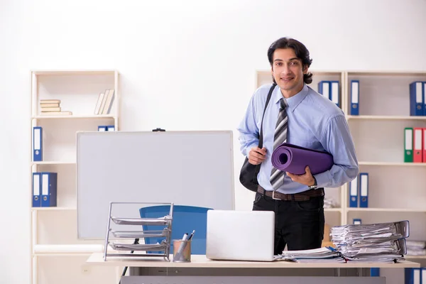 Young handsome male employee doing exercises in the office — Stock Photo, Image