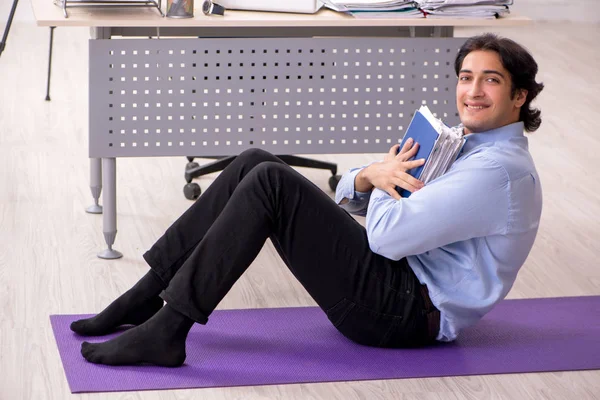 Jeune bel employé masculin faisant des exercices dans le bureau — Photo
