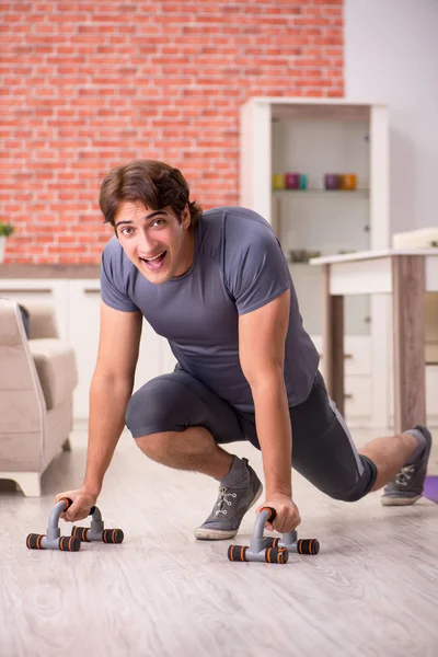 Joven hombre guapo haciendo ejercicios deportivos en casa —  Fotos de Stock