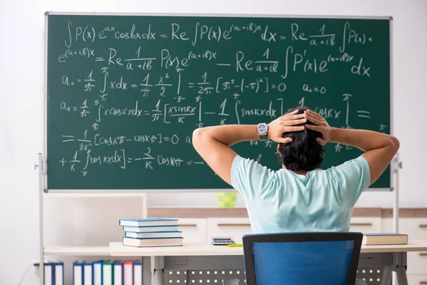 Joven matemático estudiante masculino frente a pizarra — Foto de Stock