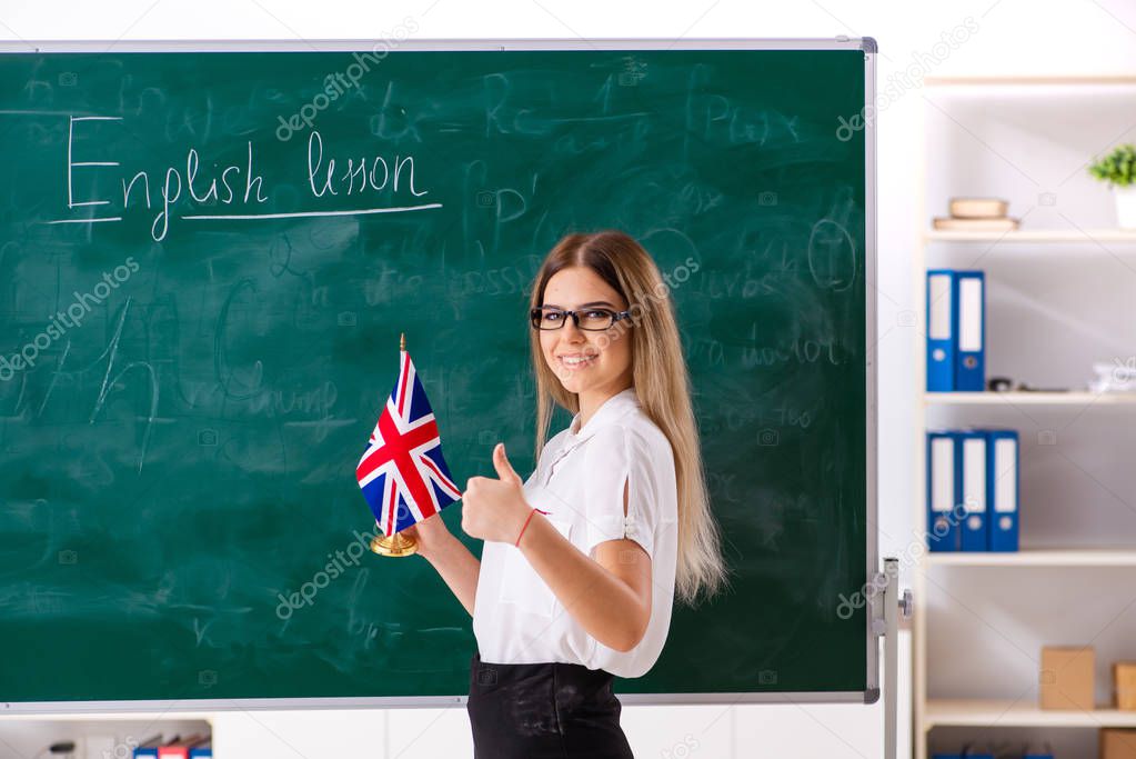 Young female english language teacher standing in front of the b