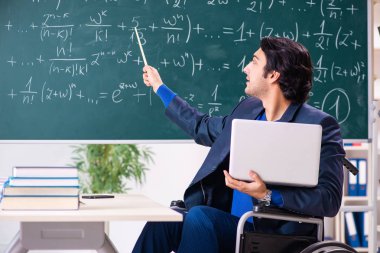 Yakışıklı delikanlı kara tahta önünde tekerlekli sandalyede 