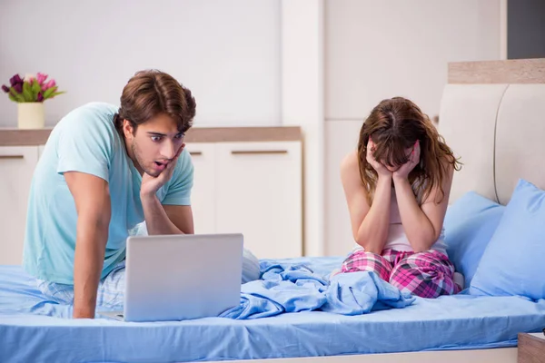 Yatak odasında dizüstü bilgisayar ile genç çift — Stok fotoğraf