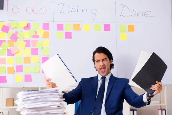 Jovem e bonito funcionário na frente do quadro branco com lista de tarefas — Fotografia de Stock