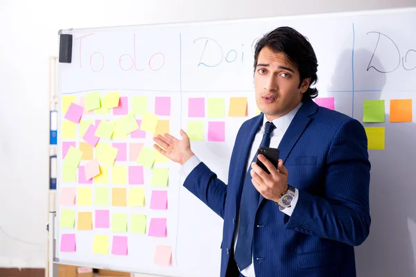 stock image Young handsome employee in front of whiteboard with to-do list  