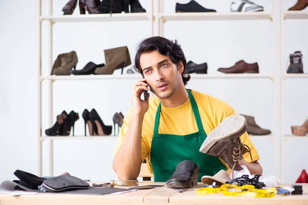 Ung man reparera skor i verkstad — Stockfoto