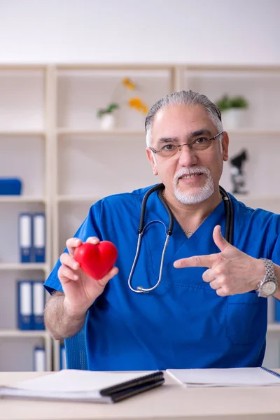 Beyaz sakallı yaşlı doktor klinikte çalışan — Stok fotoğraf