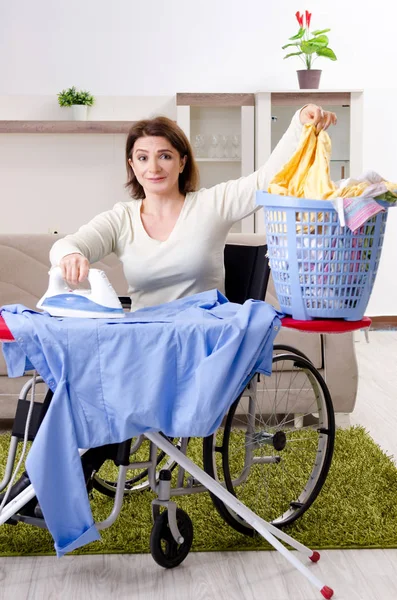Mulher em cadeira de rodas engomar em casa — Fotografia de Stock