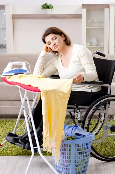 Femme en fauteuil roulant repassage à la maison — Photo