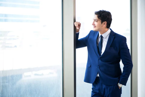 Jovem homem de negócios bonito em pé na janela — Fotografia de Stock
