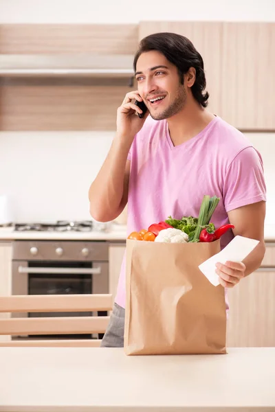 Mladý pohledný muž se zeleninou v kuchyni — Stock fotografie