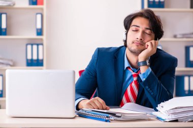 Genç yakışıklı işadamı ofiste oturuyor. 