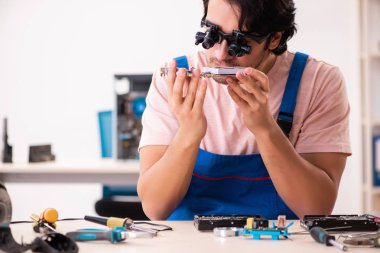 Genç bir erkek müteahhit bilgisayar tamir ediyor.  