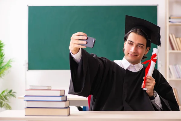 Estudante graduado na frente do quadro verde — Fotografia de Stock