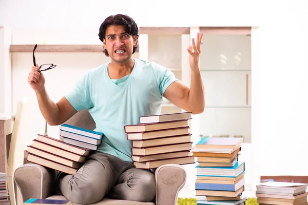 Estudante do sexo masculino com muitos livros em casa — Fotografia de Stock