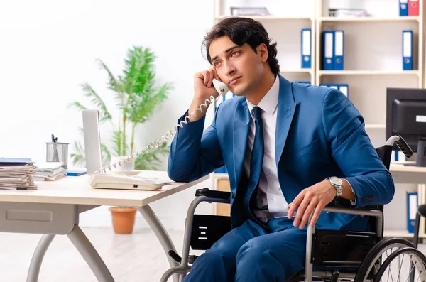 Mannelijke werknemer in rolstoel werken op kantoor — Stockfoto