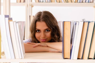 Genç kız öğrenci kütüphanede sınava hazırlanıyor. 