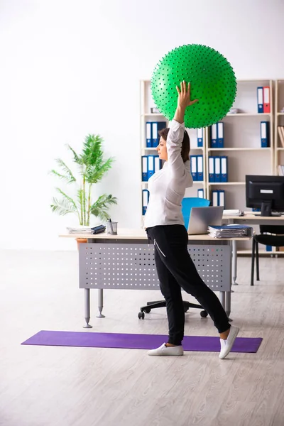 Middle-aged female employee doing exercises in the office