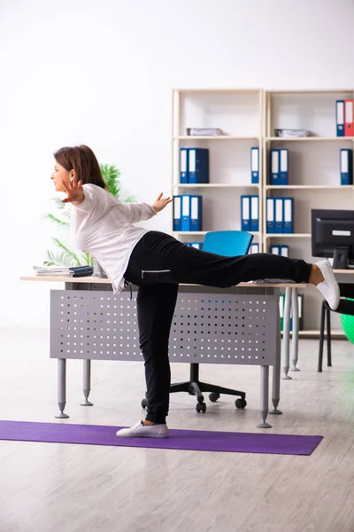 Женщина среднего возраста, выполняющая упражнения в офисе — стоковое фото