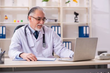 Klinikte çalışan yaşlı erkek doktor. 