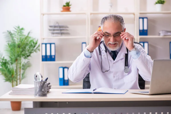 Klinikte çalışan yaşlı erkek doktor. — Stok fotoğraf