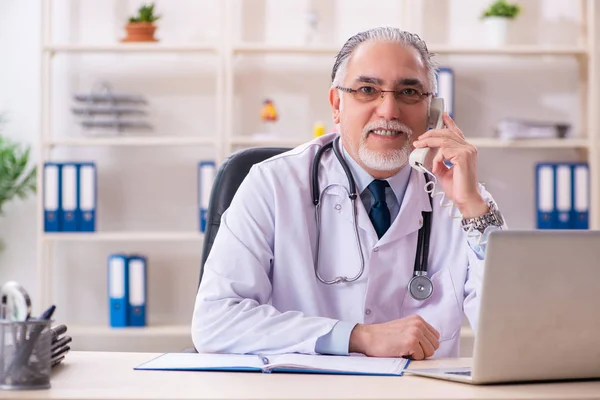 Verouderde mannelijke arts werkzaam in de kliniek — Stockfoto