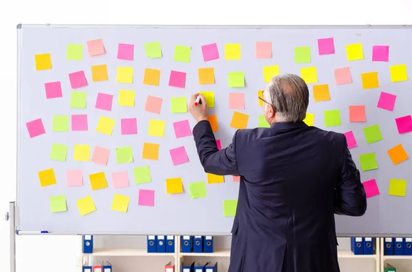 Dipendente uomo anziano in concetto di priorità contrastanti — Foto Stock