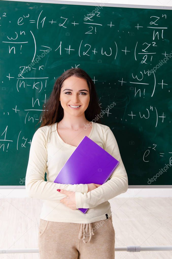 Young female math teacher in front of chalkboard  