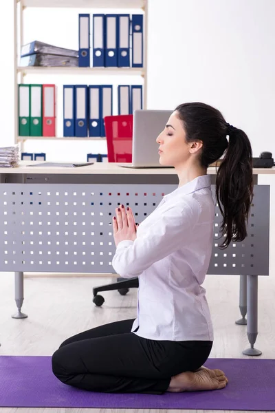 Joven empleada haciendo ejercicios en la oficina — Foto de Stock