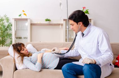 Genç, yakışıklı doktor hamile kadını ziyaret ediyor. 