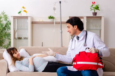 Genç, yakışıklı doktor hamile kadını ziyaret ediyor. 