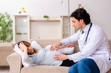 Genç, yakışıklı doktor hamile kadını ziyaret ediyor. 