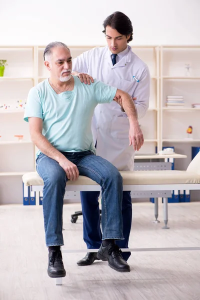 Oude man op bezoek bij jonge mannelijke arts — Stockfoto