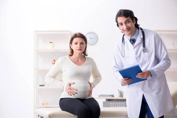 Vieille femme enceinte visitant jeune médecin masculin — Photo