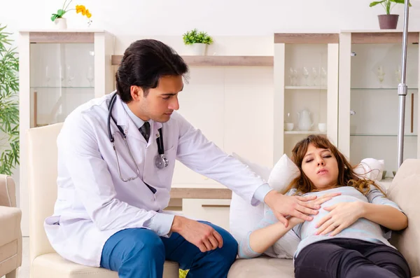 Jovem médico bonito visitando mulher grávida em casa — Fotografia de Stock