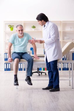 Yaşlı adam genç erkek doktoru ziyaret ediyor. 