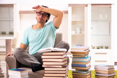 Evde pek çok kitap ile erkek öğrenci 