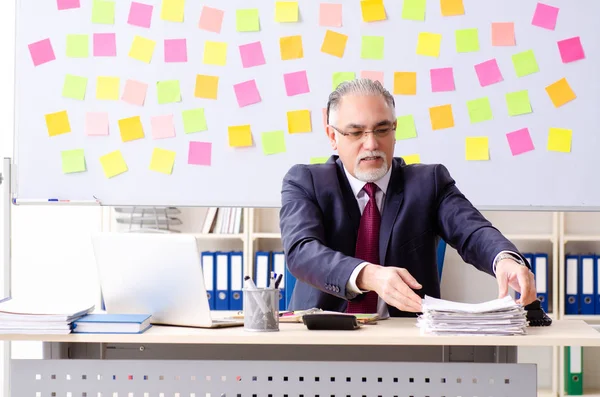 Aged man employee in conflicting priorities concept — Stock Photo, Image