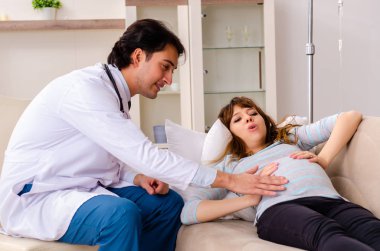 Genç, yakışıklı doktor hamile kadını ziyaret ediyor.