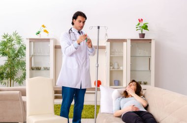 Genç, yakışıklı doktor hamile kadını ziyaret ediyor.