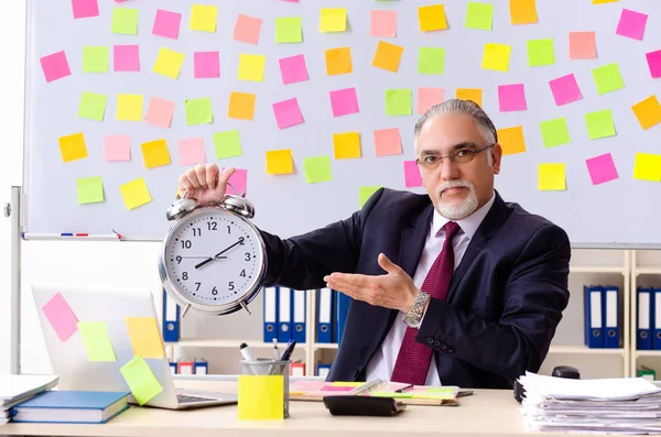 Hombre de edad empleado en el concepto de prioridades contradictorias —  Fotos de Stock