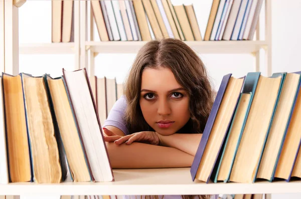 Ung kvinnlig student förbereder sig för tentamen på biblioteket — Stockfoto